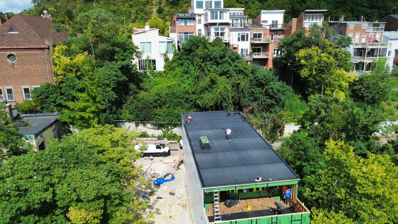 Crew working on dark flat roof, aerial view