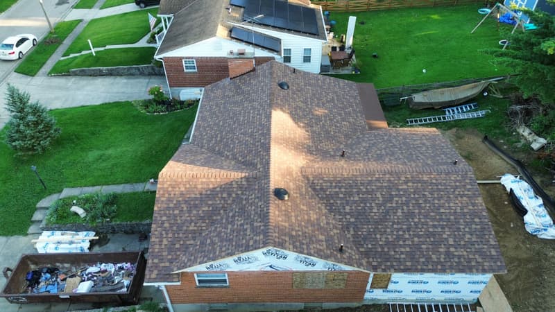 Aerial view of shingle roof with dumpster